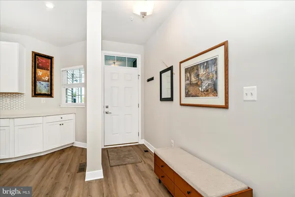 a kitchen with stainless steel appliances granite countertop a sink a microwave a refrigerator and white cabinets with wooden floor