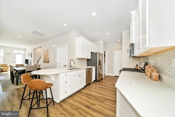 a large white kitchen with stainless steel appliances granite countertop lots of white cabinets a stove and sink