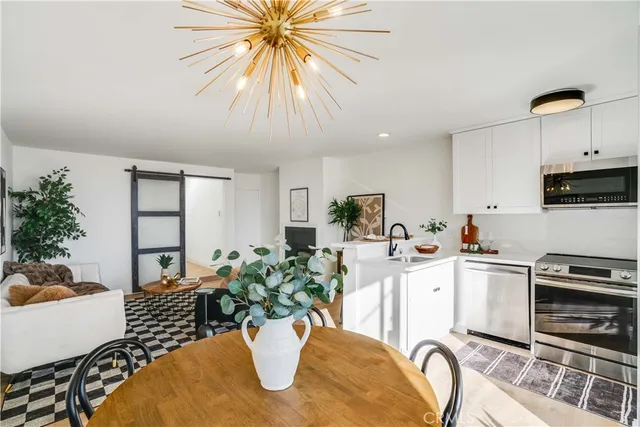 a kitchen with stainless steel appliances kitchen island granite countertop a dining table chairs and white cabinets