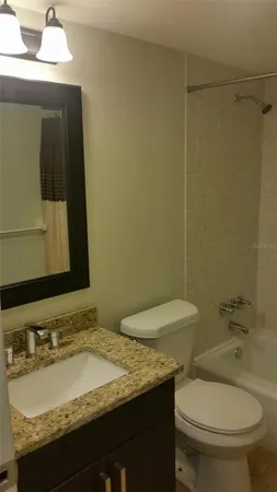 a bathroom with a granite countertop sink toilet and mirror