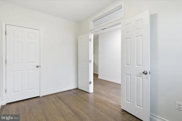 an empty room with wooden floor and closet area