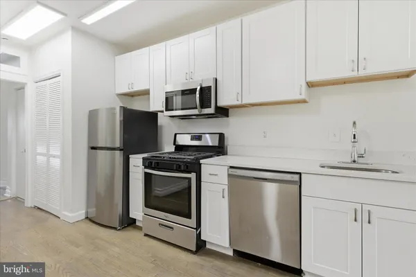 a kitchen with stainless steel appliances granite countertop white cabinets a sink a stove a refrigerator and white cabinets