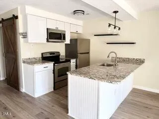 a kitchen with kitchen island granite countertop a sink stove and refrigerator