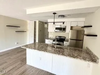 a kitchen with kitchen island granite countertop a refrigerator and a sink