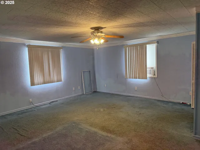 en empty room with windows and chandelier fan