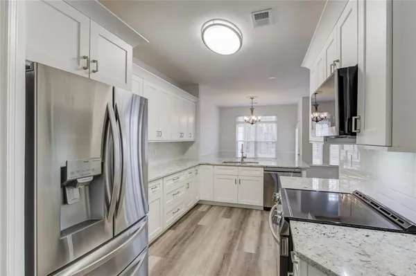 a kitchen with granite countertop a refrigerator stove and sink