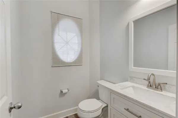 a bathroom with a toilet a sink a mirror and vanity