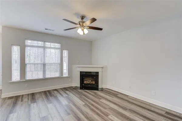 a view of an empty room with wooden floor fireplace and a window
