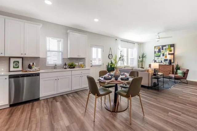 a kitchen with a table chairs a sink dishwasher window and cabinets