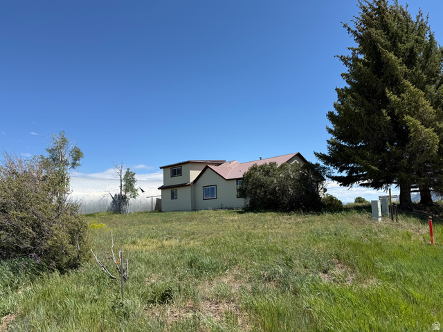 2002 Lund Road Bancroft, ID 83217 - Photo 28 of 28 Two-story residence with light-colored siding and a reddish-brown roof, situated on a grassy landscape