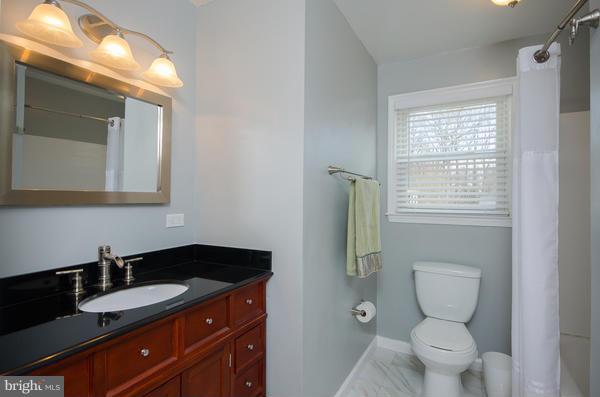 8011 Langbrook Road Springfield, VA 22152 - Photo 18 of 30 a bathroom with a granite countertop toilet a sink and a mirror