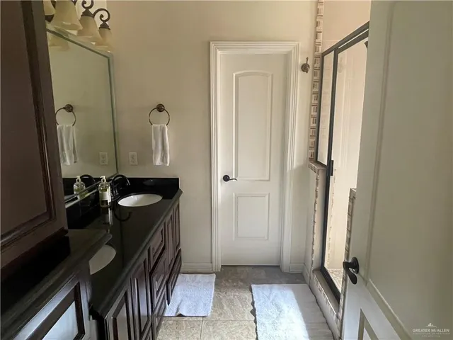 a bathroom with a granite countertop sink a mirror and shower
