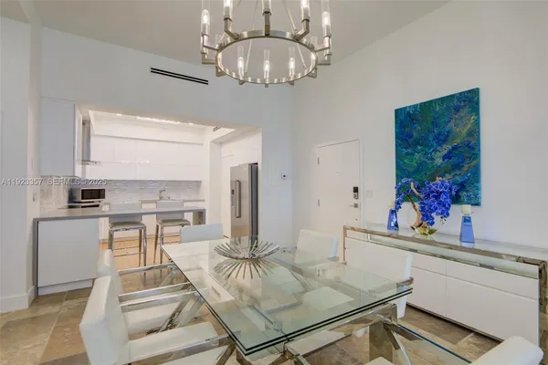 a living room with stainless steel appliances furniture a chandelier and a dining table