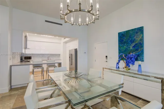 a living room with stainless steel appliances furniture a chandelier and a dining table