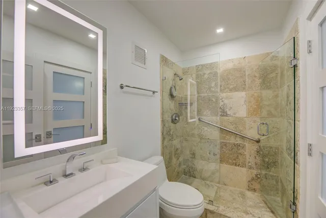 a bathroom with a sink toilet a mirror and shower