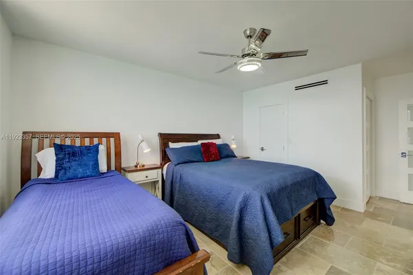 a bedroom with two beds and ceiling fan