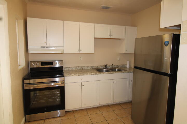 a kitchen with granite countertop white cabinets and refrigerator