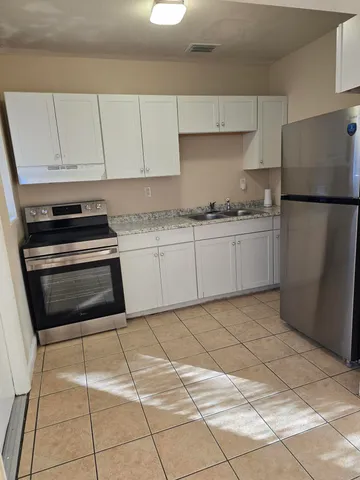 a kitchen with granite countertop a stove a refrigerator and cabinets
