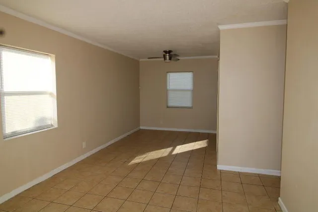 a view of an empty room with window and chandelier fan