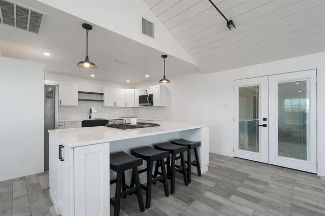 a kitchen with stainless steel appliances kitchen island a wooden floor and white cabinets