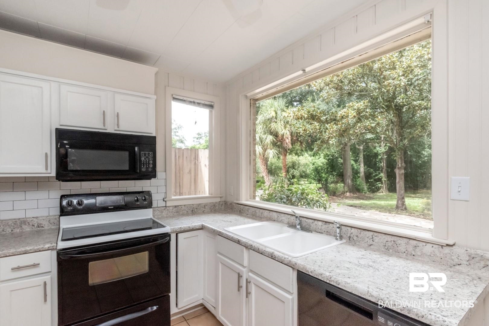 1906 Old Shell Road Mobile, AL 36607 - Photo 9 of 26 Kitchen with white cabinets, backsplash, range with electric cooktop, and sink