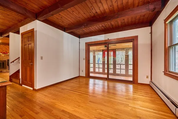 a view of an empty room with wooden floor and a window