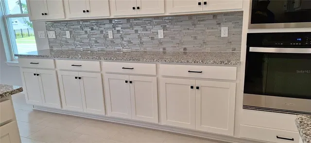 a kitchen with granite countertop white cabinets and white appliances