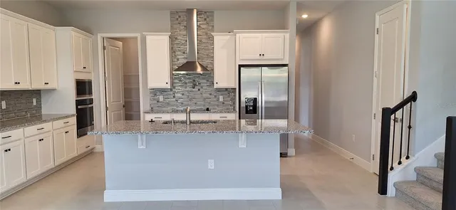 a large kitchen with stainless steel appliances granite countertop a granite counter tops and a view of living room