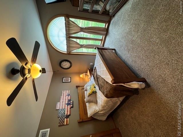 4457 Bradley Road Gregory, MI 48137 - Photo 77 of 79 Arched window with decorative blinds, ceiling fan with integrated lighting, wood-framed bed, light brown wall color, and carpeted flooring