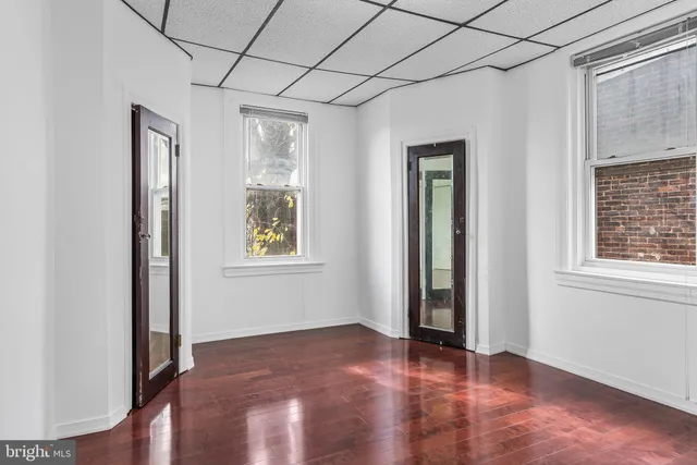 an empty room with wooden floor and windows