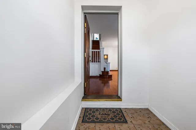 a view of a hallway with wooden floor and a living room