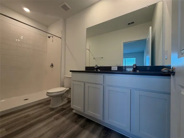 a bathroom with a granite countertop sink a toilet and a mirror