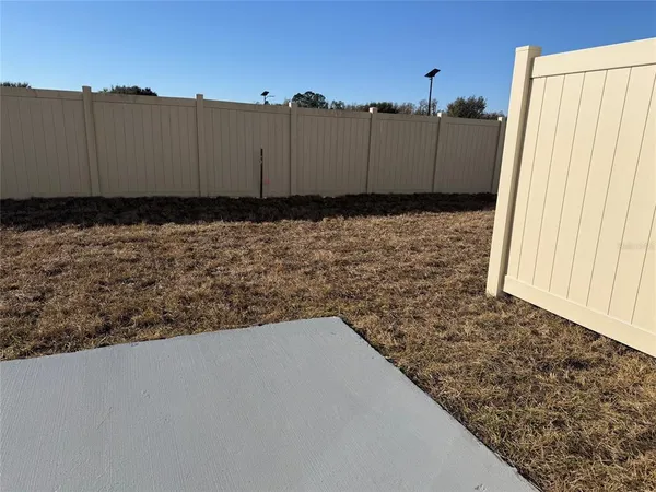 a view of a dry yard with wooden fence