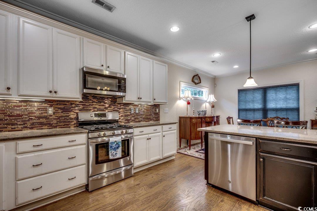 908 Corrado Street Myrtle Beach, SC 29572 - Photo 16 of 33 Kitchen featuring appliances with stainless steel finishes, light stone countertops, decorative backsplash, light wood-style flooring, and crown molding