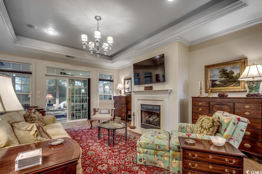 908 Corrado Street Myrtle Beach, SC 29572 - Photo 2 of 33 Living area featuring a tray ceiling, a fireplace, crown molding, and a chandelier