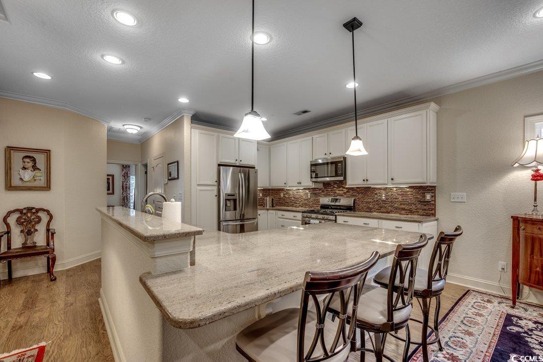 908 Corrado Street Myrtle Beach, SC 29572 - Photo 3 of 33 Kitchen with crown molding, a kitchen breakfast bar, appliances with stainless steel finishes, light stone countertops, and a spacious island