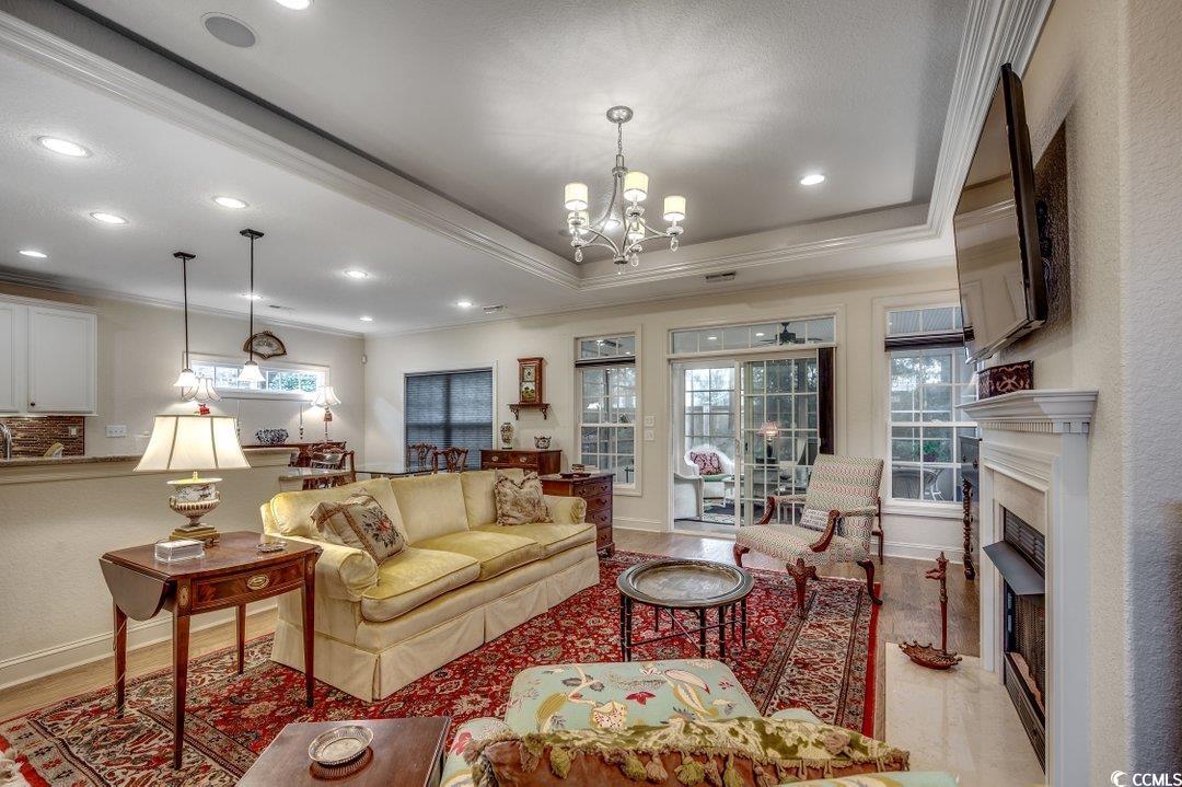 908 Corrado Street Myrtle Beach, SC 29572 - Photo 4 of 33 Living room with ornamental molding, a raised ceiling, a fireplace, light wood finished floors, and a chandelier