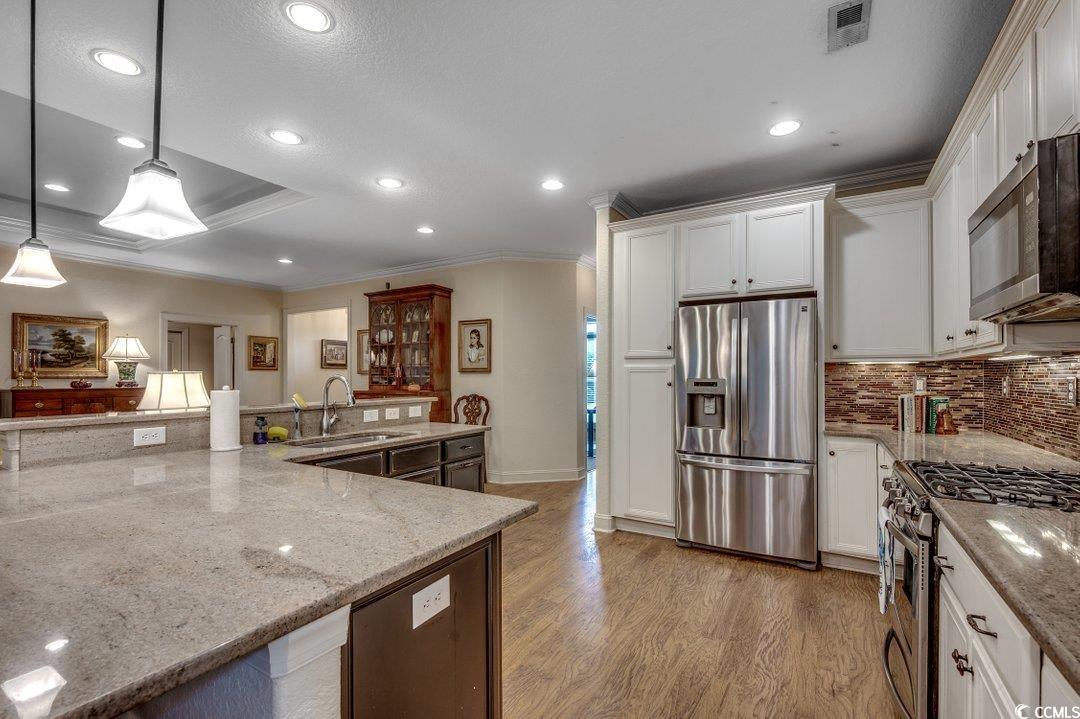 908 Corrado Street Myrtle Beach, SC 29572 - Photo 7 of 33 Kitchen featuring appliances with stainless steel finishes, crown molding, light stone countertops, decorative backsplash, and recessed lighting