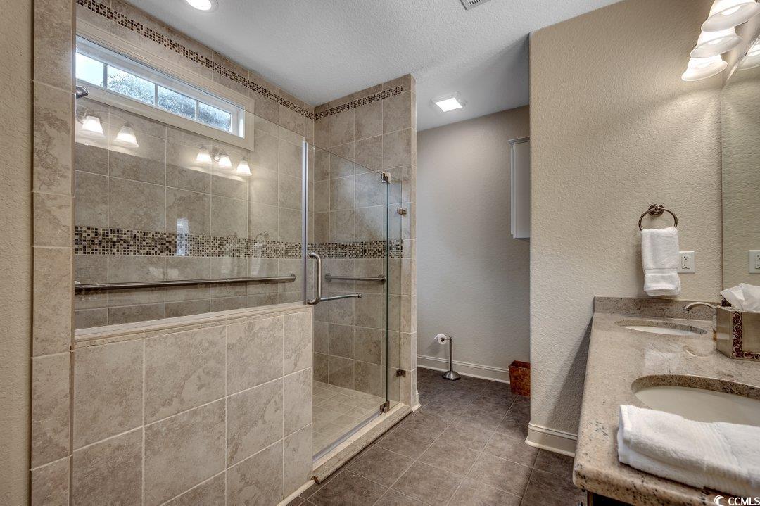 908 Corrado Street Myrtle Beach, SC 29572 - Photo 10 of 33 Full bath featuring a shower stall, double vanity, dark tile patterned floors, a textured wall, and a textured ceiling