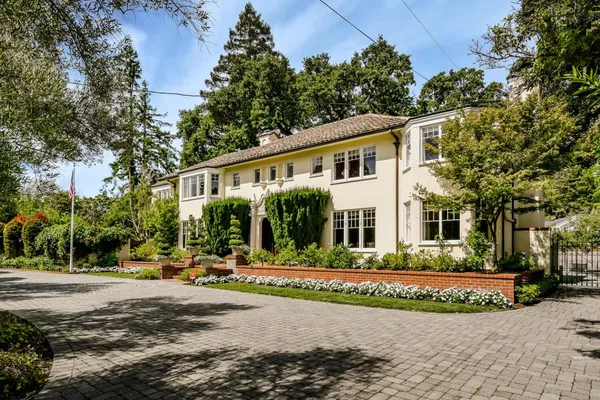 a front view of a house with a garden and tree