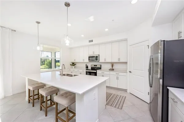 a large white kitchen with stainless steel appliances granite countertop lots of counter space a sink and a center island