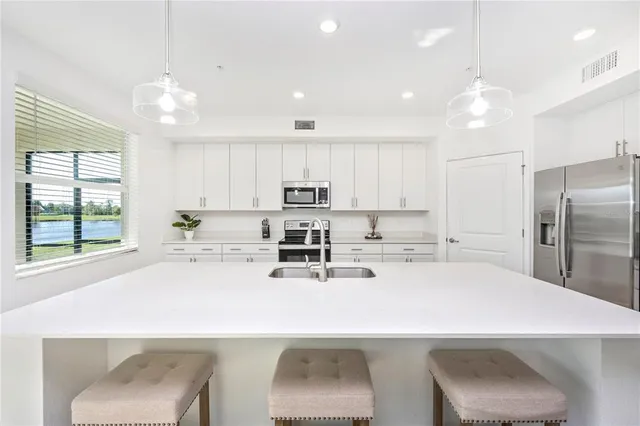 a living room with white couches and kitchen view with wooden floor