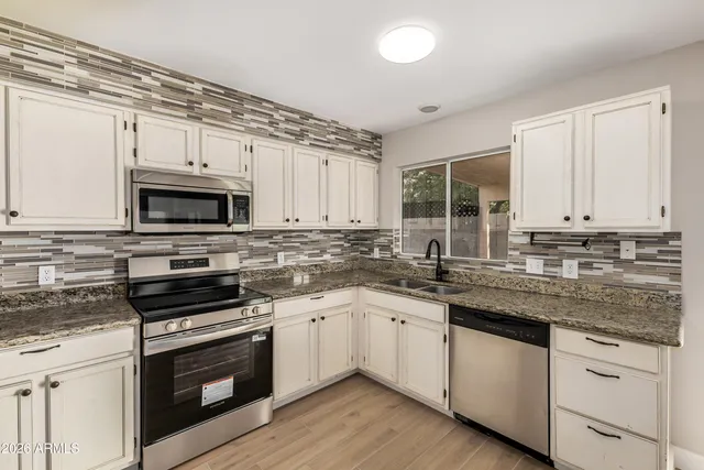 a kitchen with granite countertop a sink cabinets stainless steel appliances and a counter space