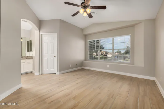 a view of an empty room with a window and wooden floor