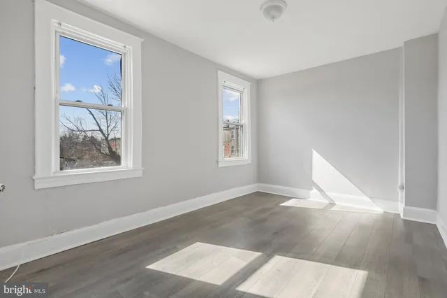an empty room with wooden floor and windows
