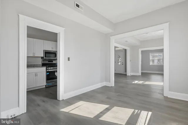 a view of a kitchen and an empty room with wooden floor and a kitchen