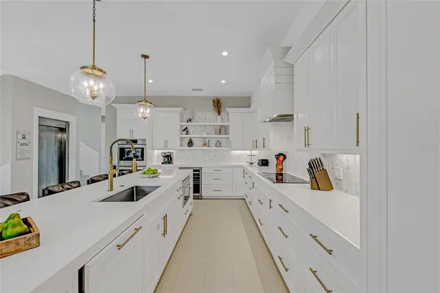 a large white kitchen with lots of counter space and stainless steel appliances