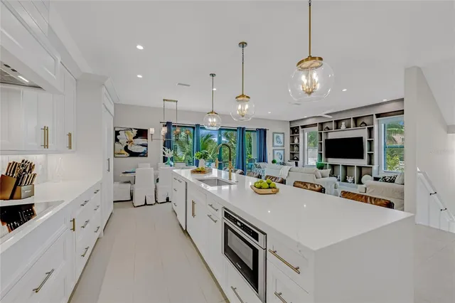 a large white kitchen with a stove a sink a center island and furniture