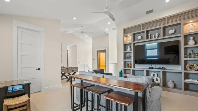 a living room with stainless steel appliances kitchen island granite countertop a table chairs sink and a flat screen tv