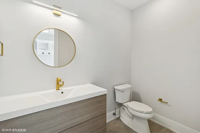 a bathroom with a toilet a sink a mirror and vanity